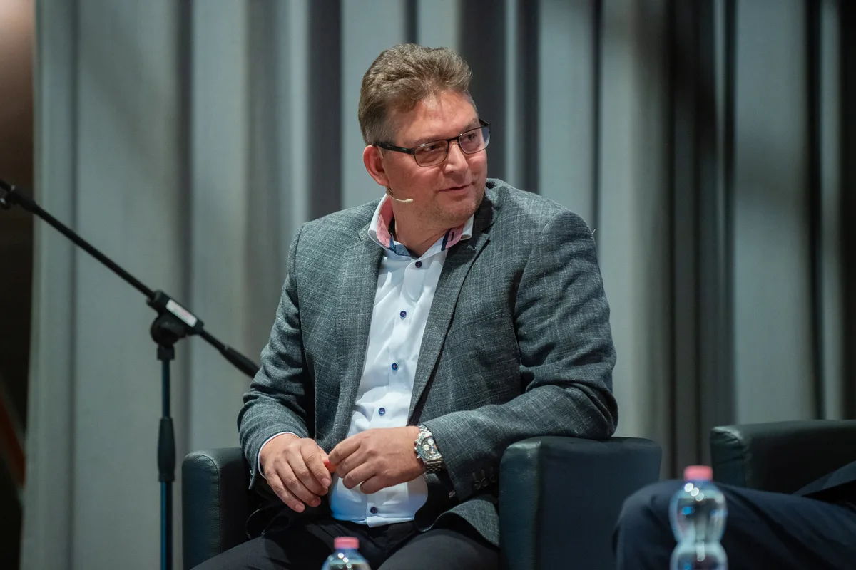 Ein Mann in einem grauen Anzug blickt nach rechts.
